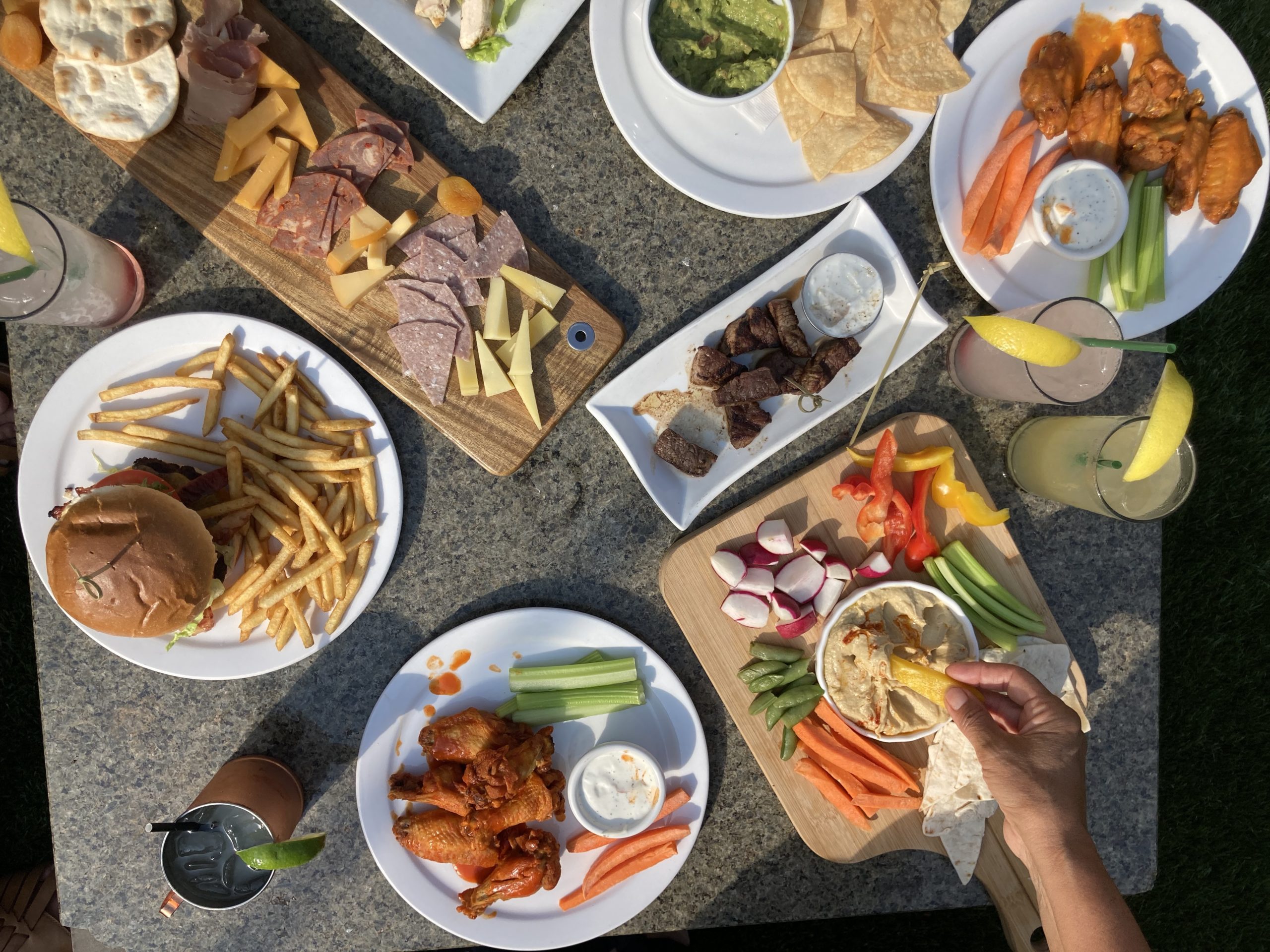 food and drinks on a table with hand reaching for food