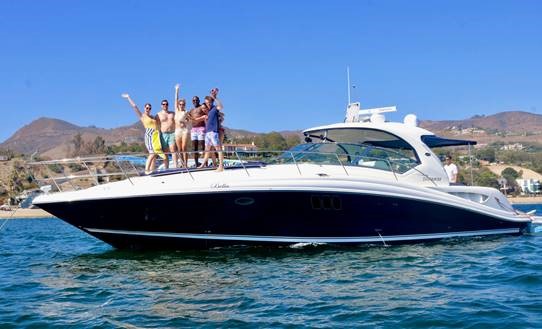 Friends standing on bow of power boat in the ocean with mountains in background