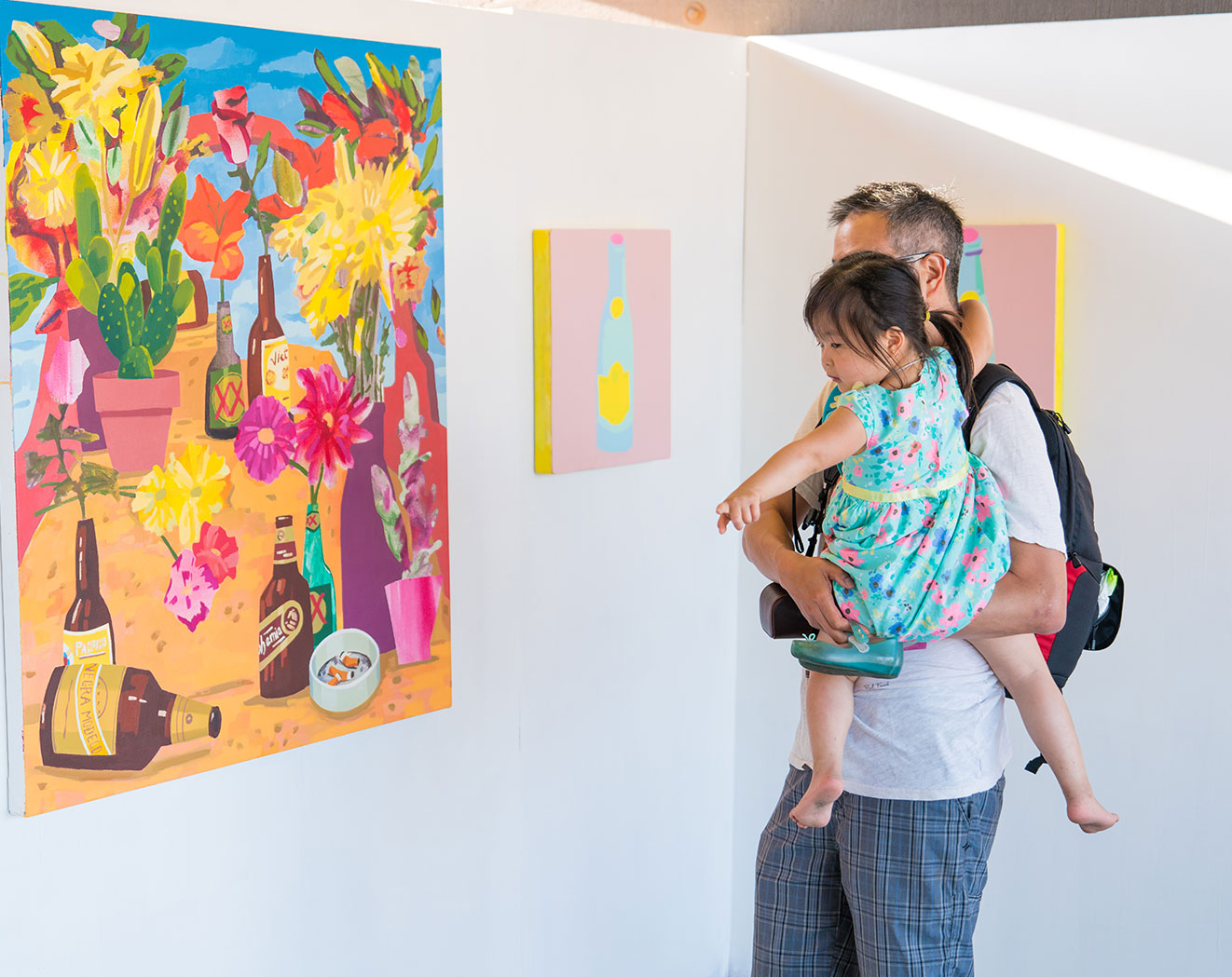 father holding child and looking at artsea art wall