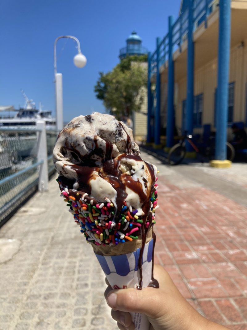 Double scoop of ice cream with chocolate syrup dripping down a cone