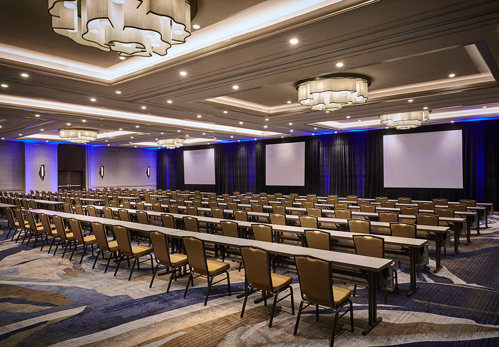 conference room set up with chairs and tables. Presentation screens in front of room