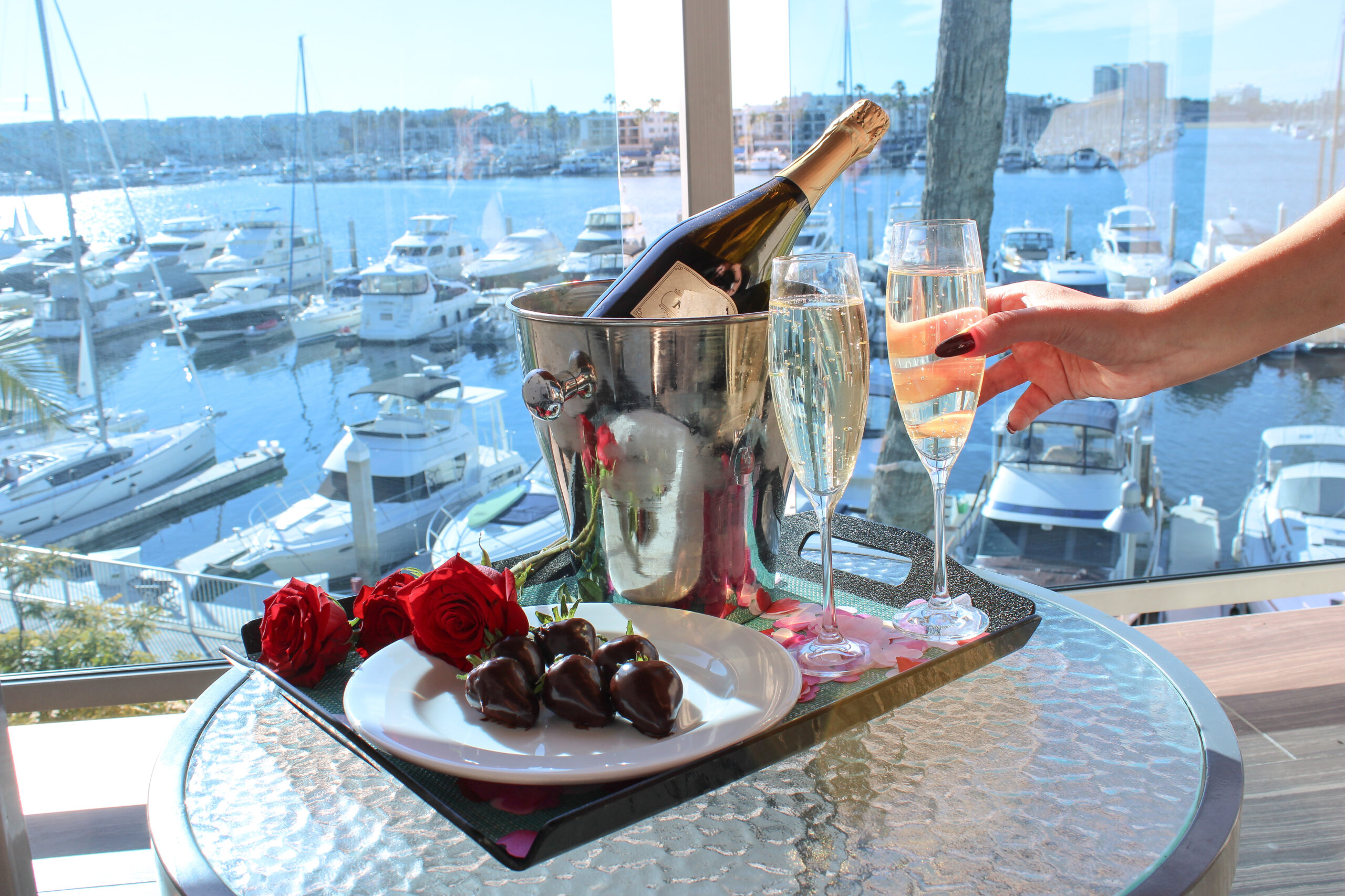 Champagne bottle, glass and chocolates with view of marina